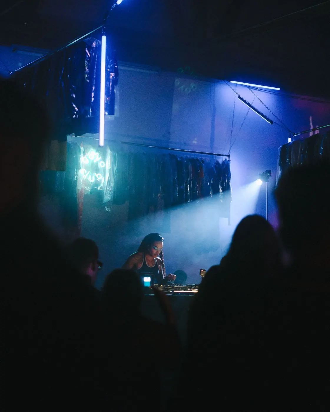 Crowd silhouettes gathered near the booth in colorful blue-green ambient light
