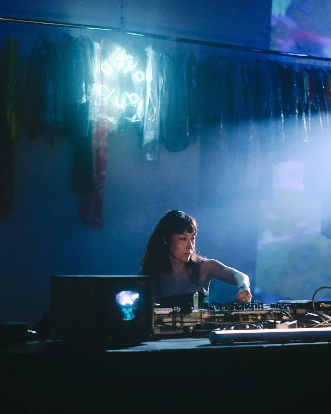 Woman DJ mixing under dramatic uplighting from the booth