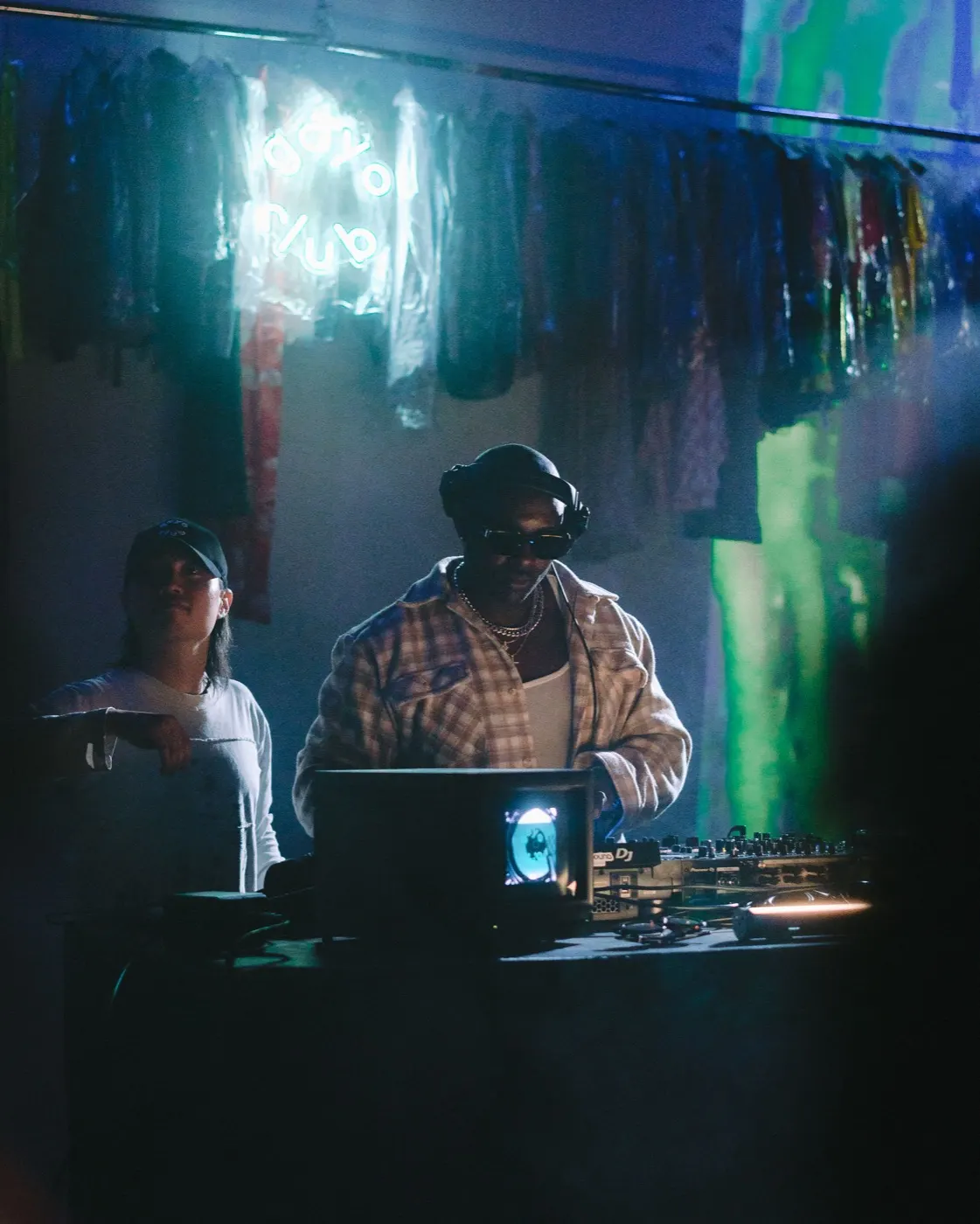 Two DJs together at the decks, one gesturing mid-set