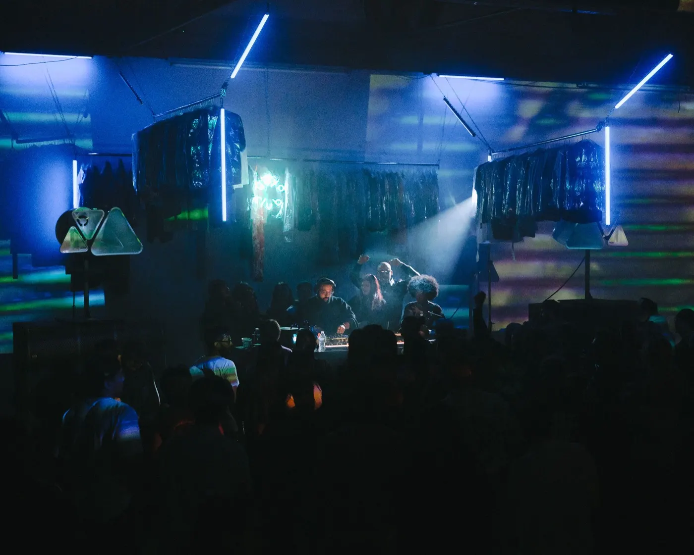 Wide colorful shot of the crowd and stage with green and blue triangular light shapes