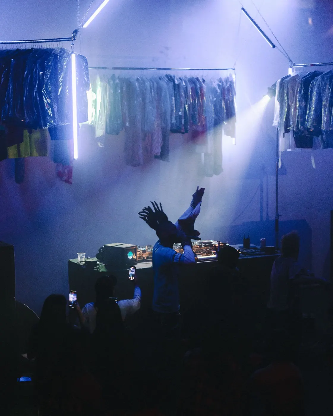 DJ caught mid-motion with an arm thrown up, dynamic energy at the decks