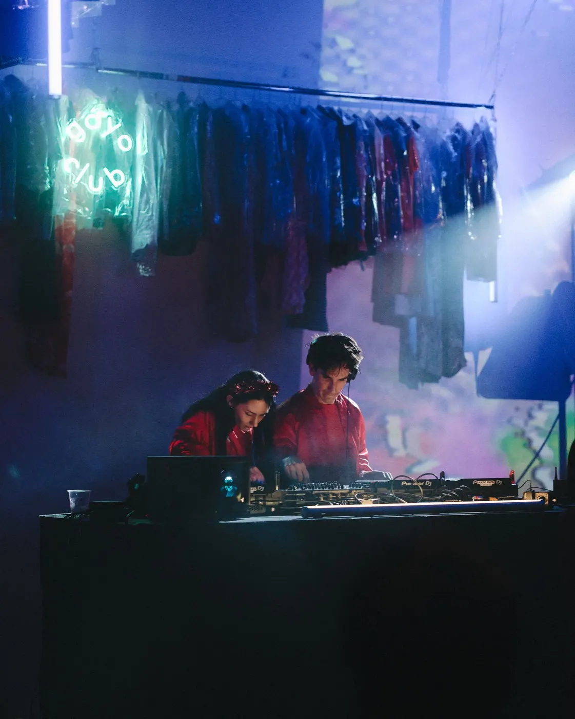 Trio of performers at the booth wearing headphones, lit in red and green