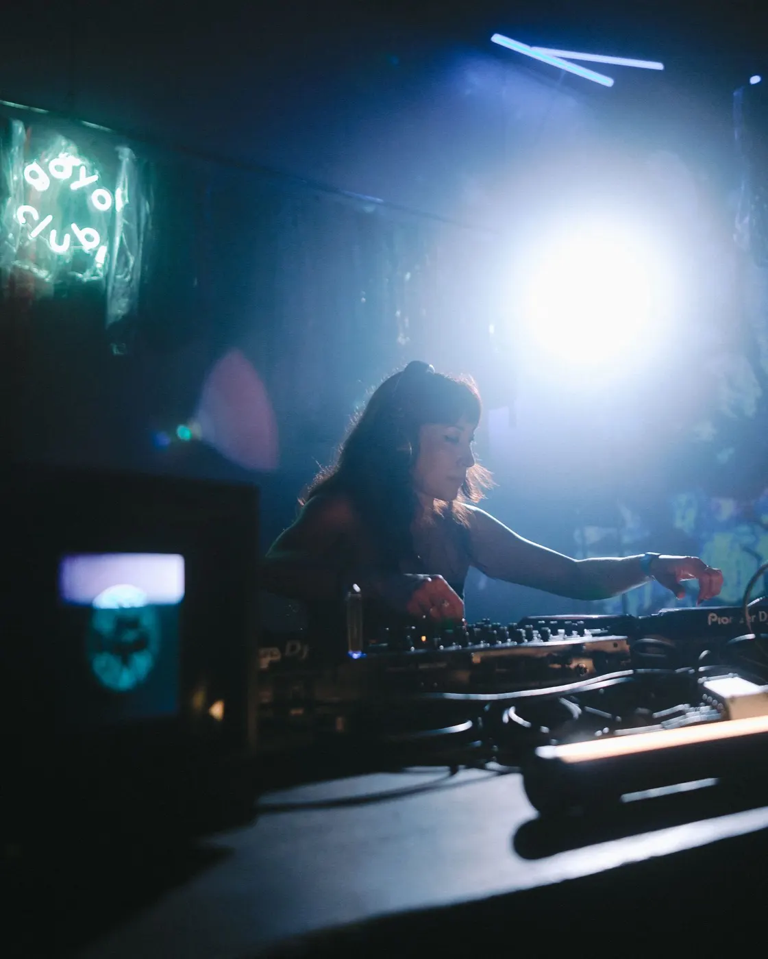 DJ silhouetted against a colorful hanging tapestry behind the booth