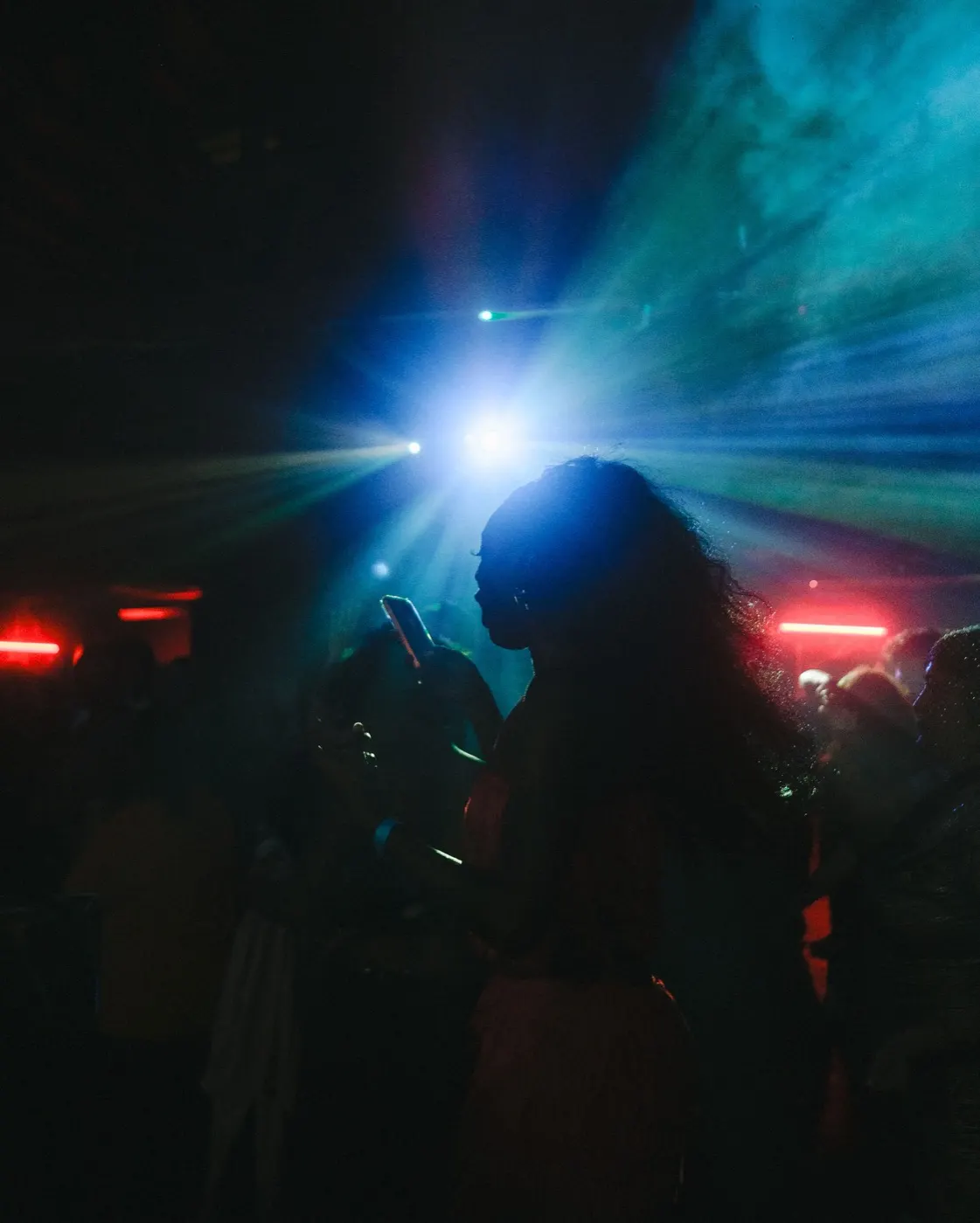 Colorful laser light burst overhead with the crowd silhouetted, looking up