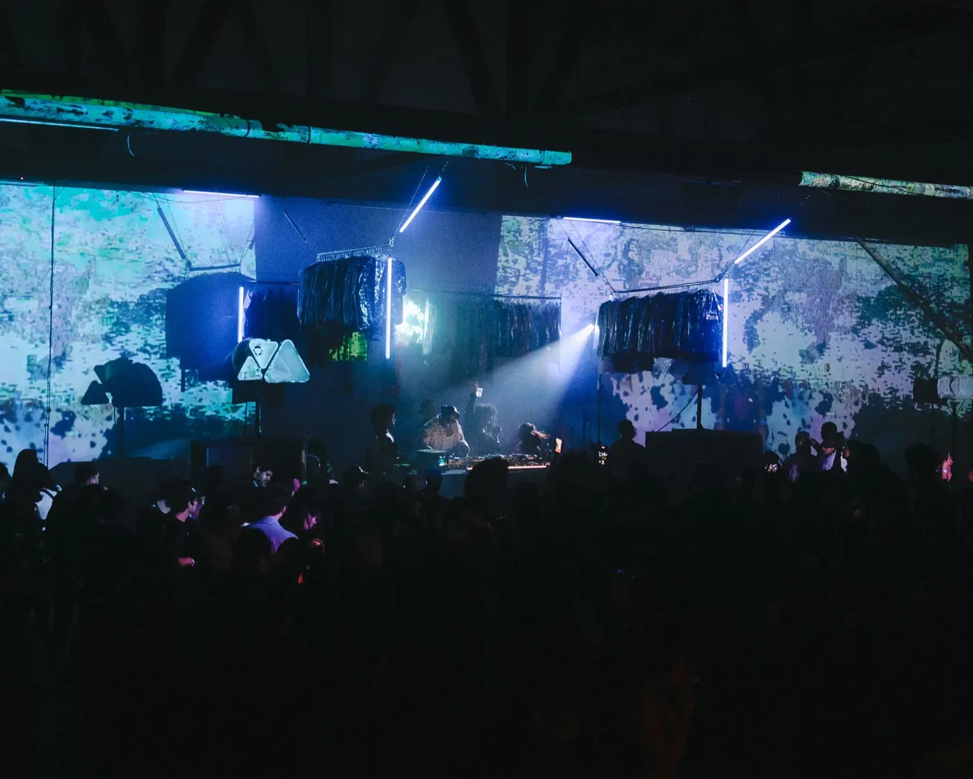 Wide venue shot with light beams crossing over the dense crowd and colorful projected backdrop