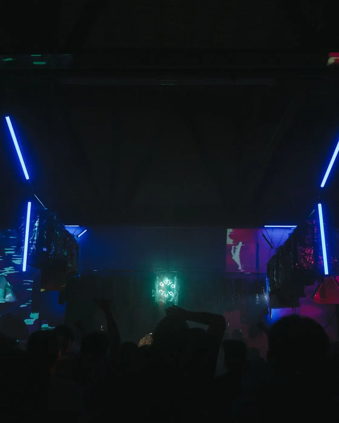 Wide interior shot with diagonal blue neon beams crossing over the crowd
