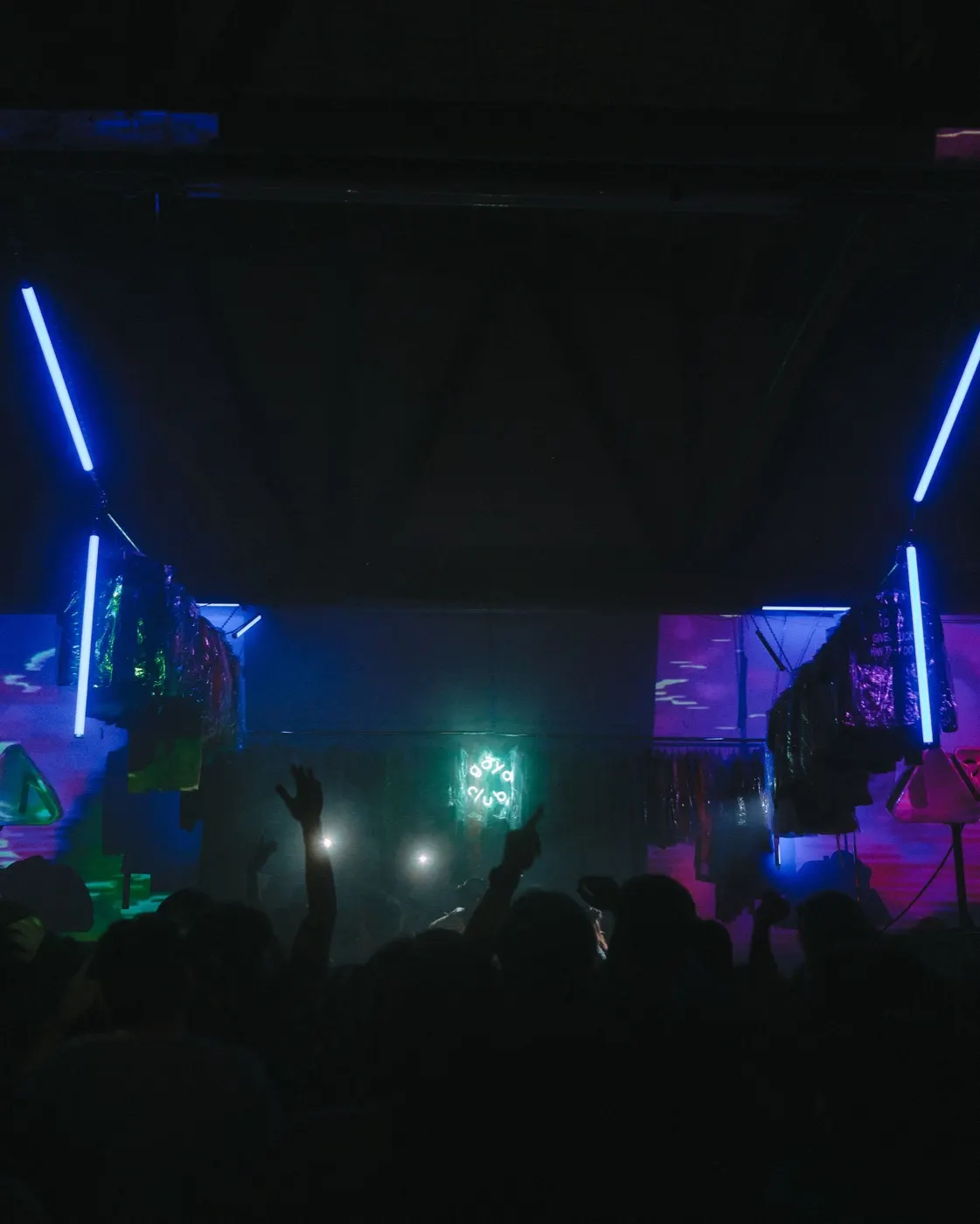 Wide shot with diagonal light beams and colorful triangular shapes over the crowd