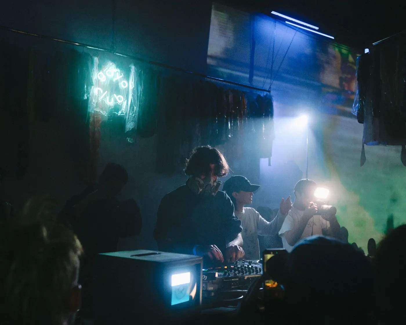 Trio of DJs performing together at the booth under colorful light