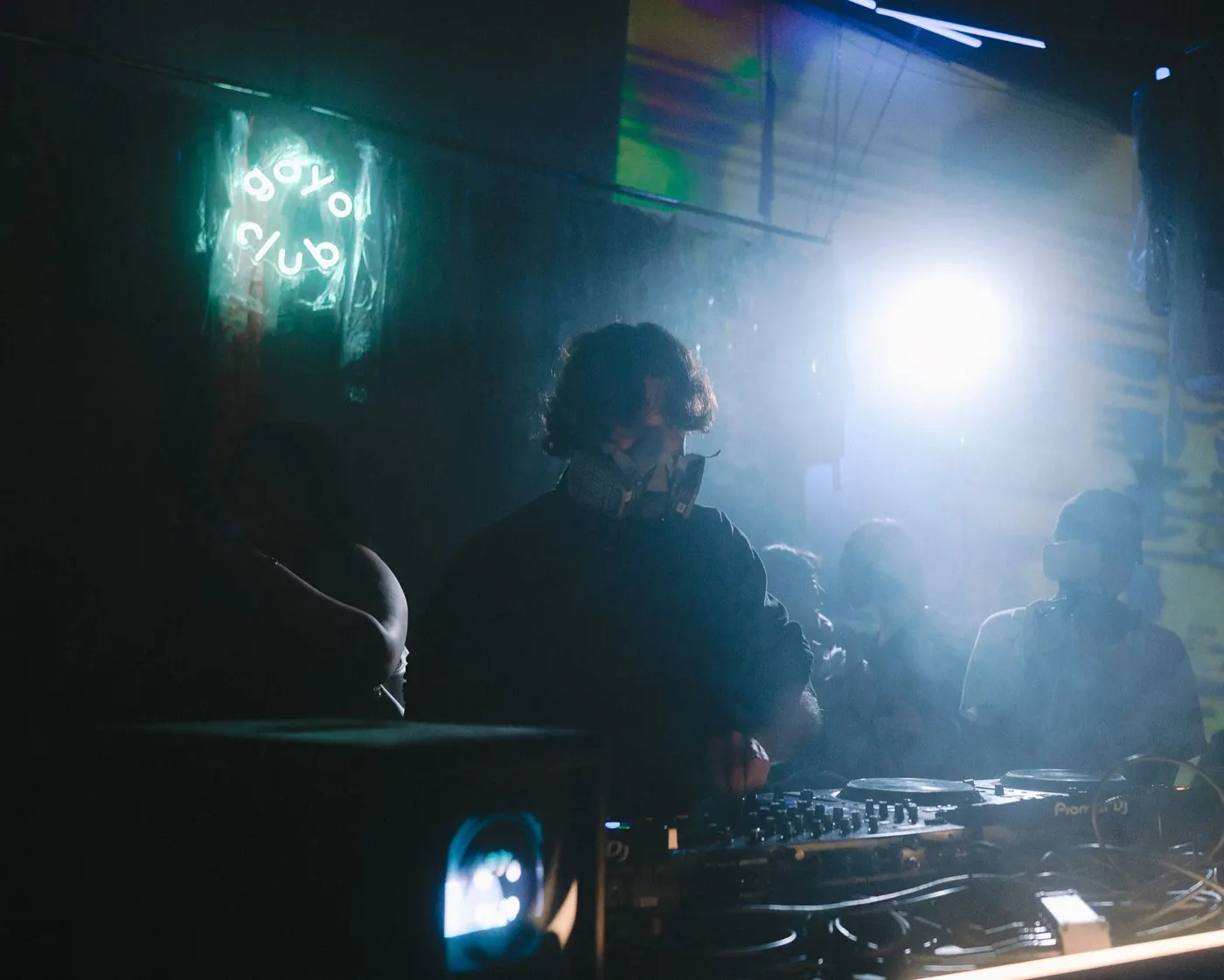 Close-up of a DJ wearing headphones, bright backlight behind