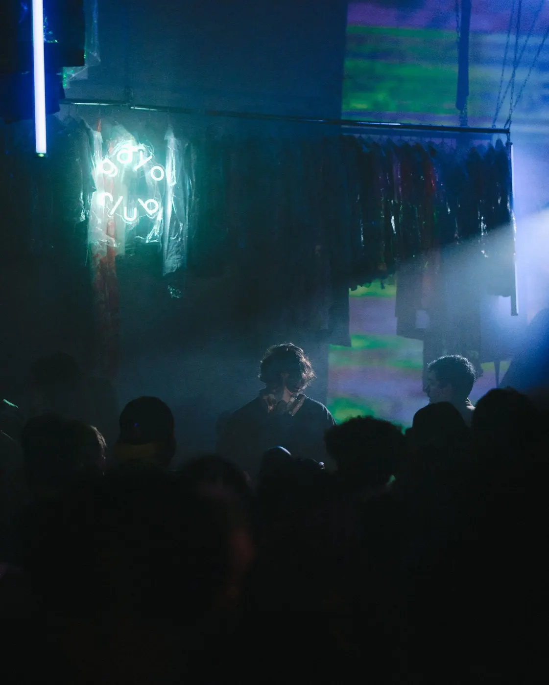 Crowd silhouettes gathered near the booth in blue-green colorful light
