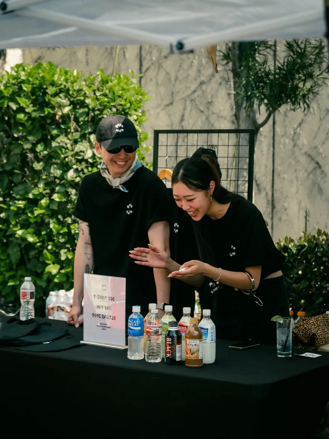 Two staff members smiling behind the drinks table