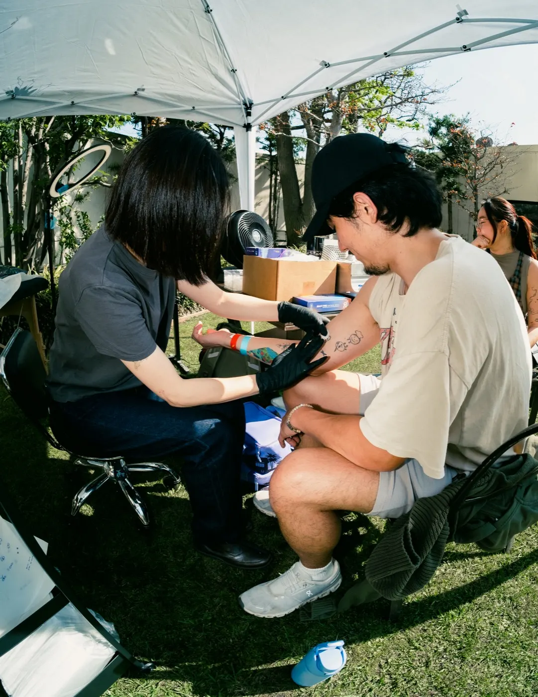 A guest getting a tattoo at an outdoor tattoo booth