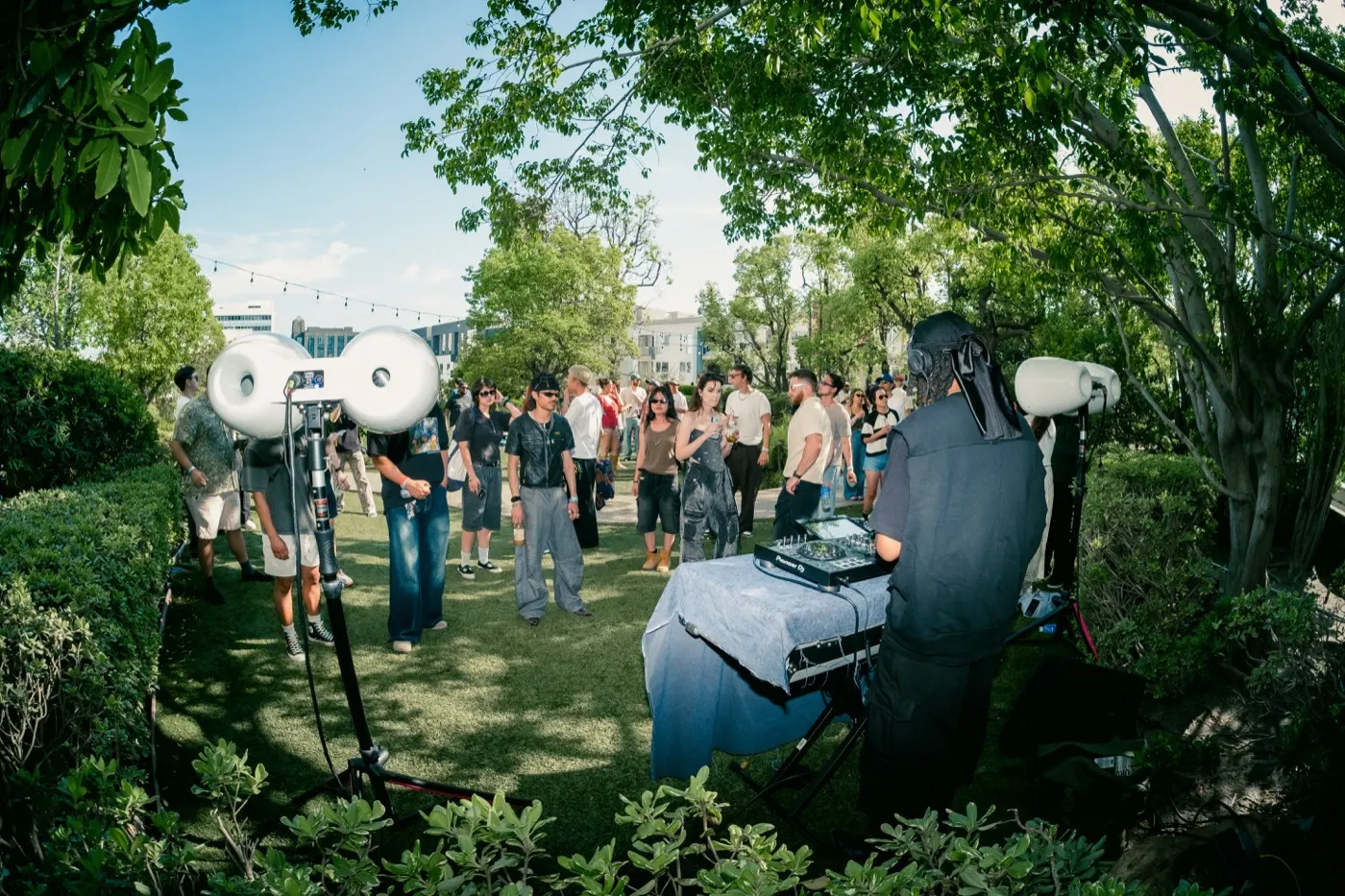 Wide view of the DJ setup with large speakers framed by trees