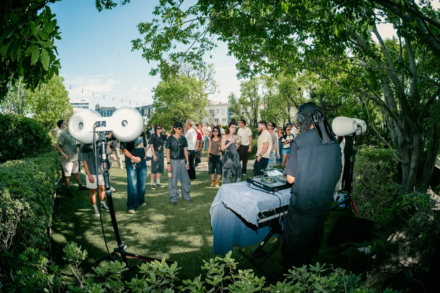 Wide view of the DJ setup and speakers in the Japanese garden as the crowd gathers