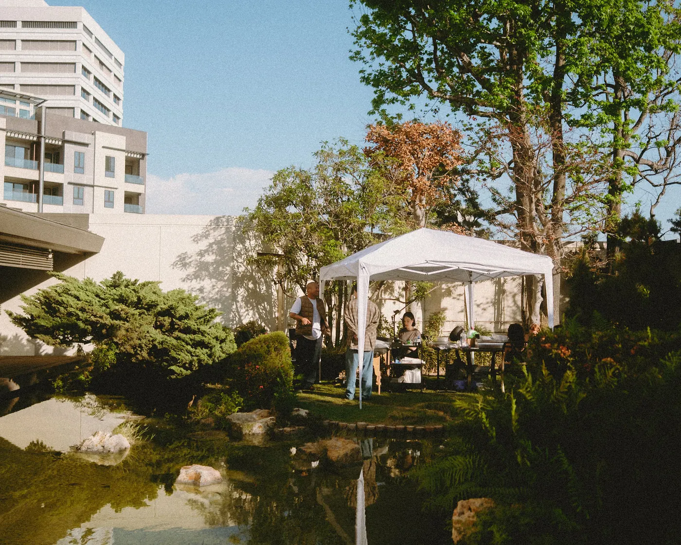 White canopy tent reflected in the garden pond during the daytime party