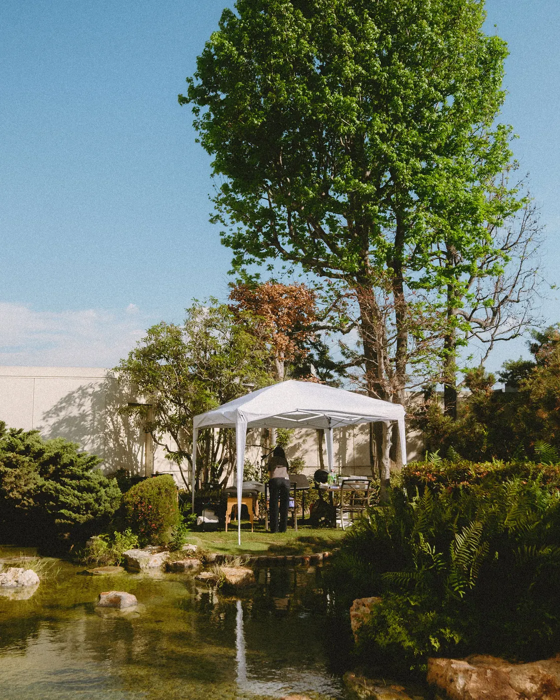 Guests by the garden pond beside the white event tent