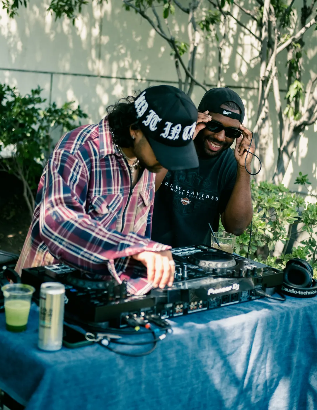 Two DJs behind the decks with matcha cans on the table