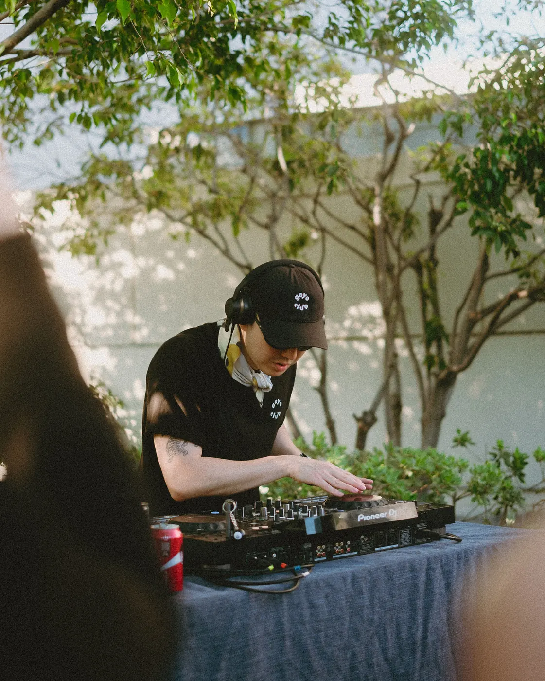 DJ mixing behind the decks in the shade