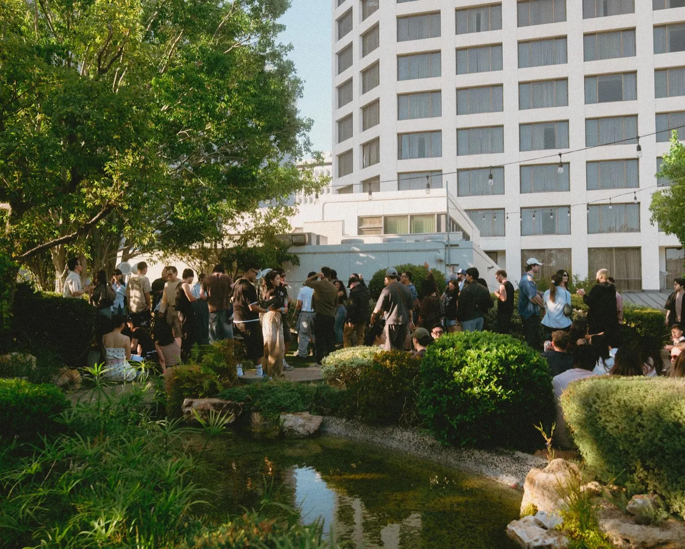 Wide view of the Japanese garden venue with the koi pond and hotel tower behind guests