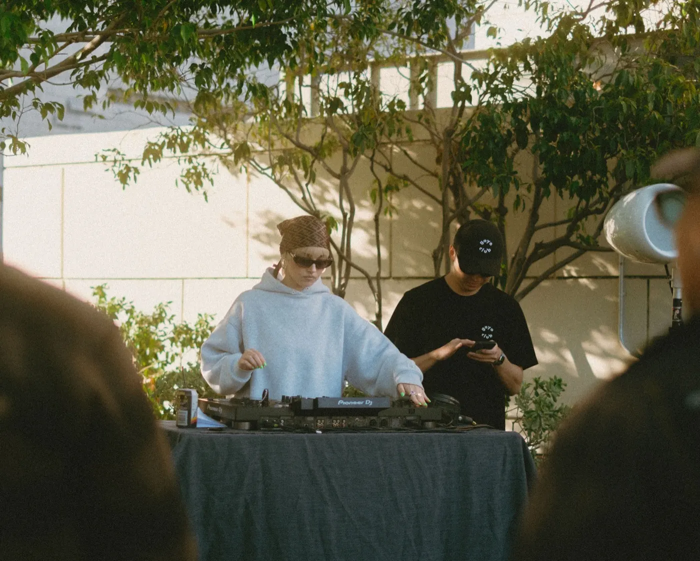 DJ in a beanie and sunglasses performing at the outdoor decks