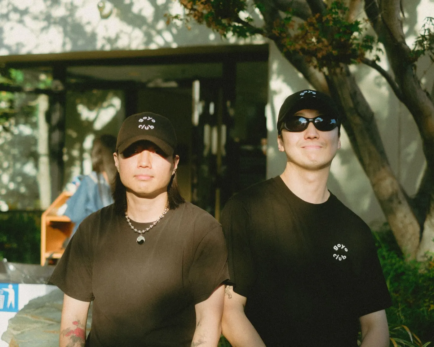 Two attendees in goyo club t-shirts and caps posing for a portrait